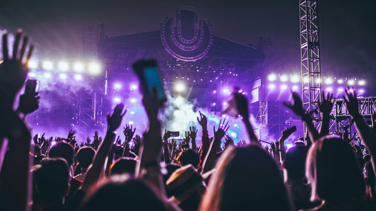 Crowd with raised hands in front of a lit concert stage