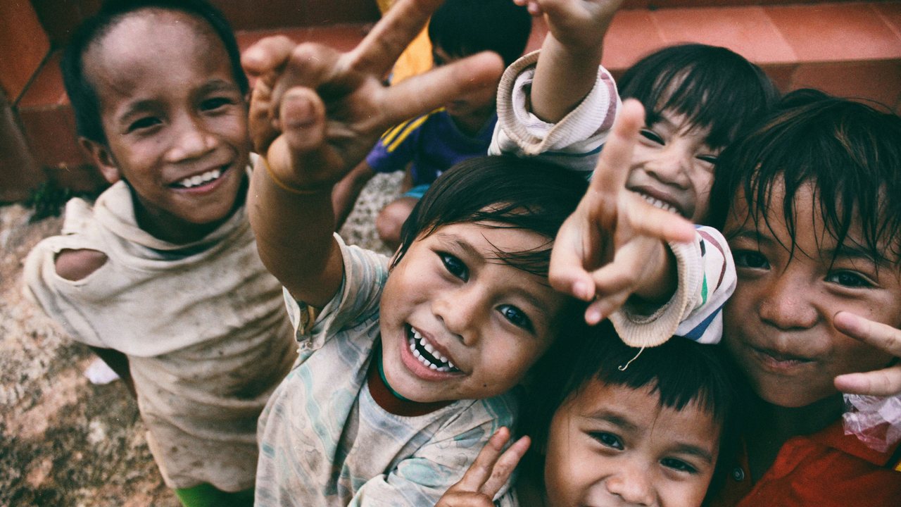 Group of smiling children reaching towards the camera