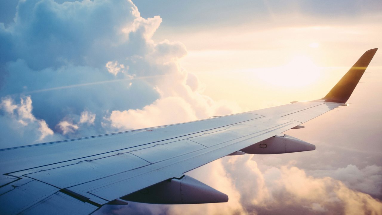 Aircraft wing above the clouds at sunset, seen from the cabin