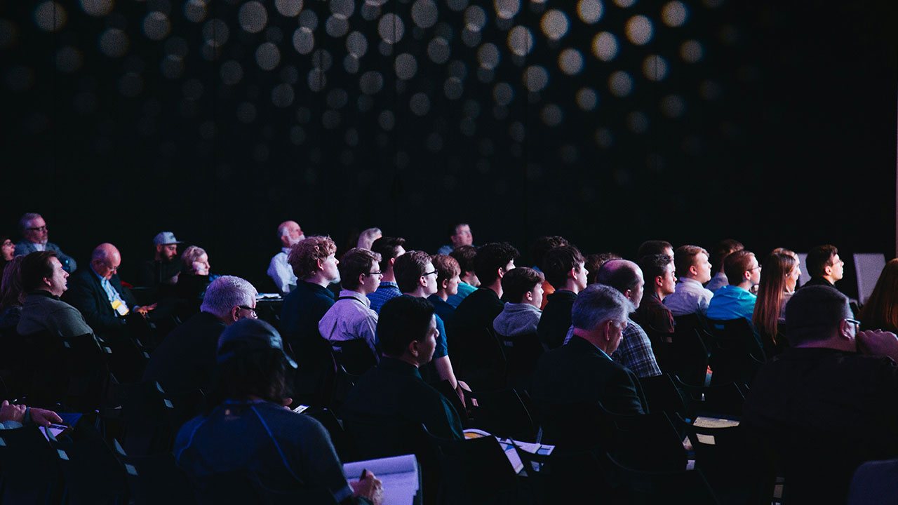 Audience seated in a darkened auditorium at a press event